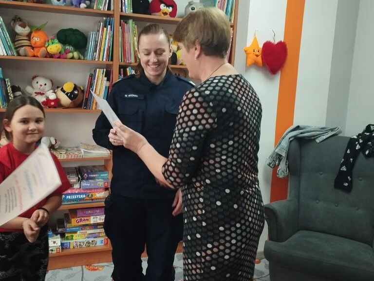 Bibliotekarka przekazuje policjantce dyplom dziękczynny za pomoc w zajęciach.