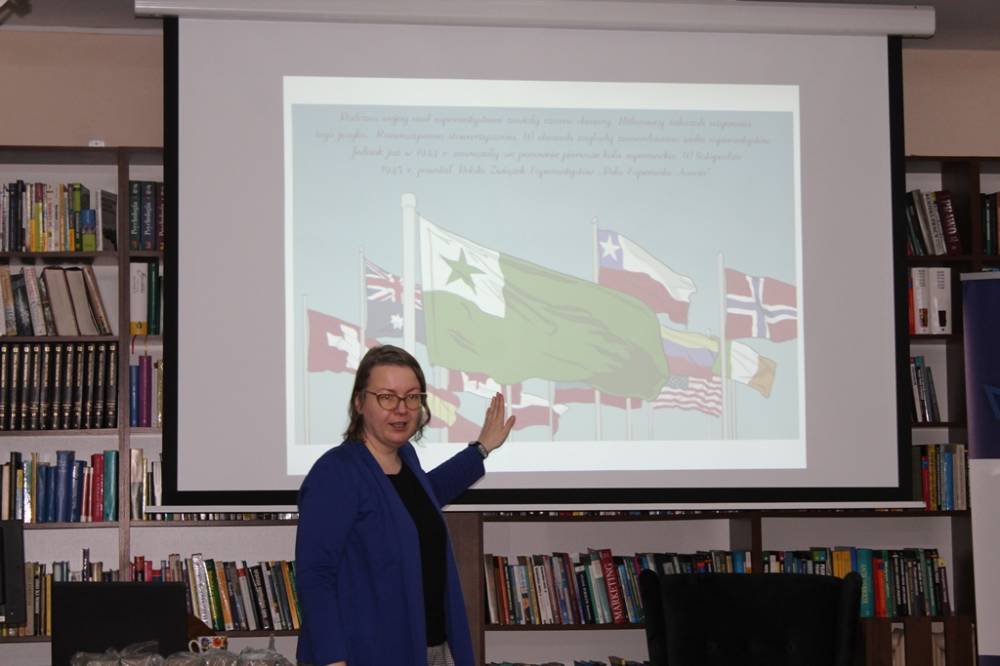 Pani Magda wskazuje na wyświetlaną na ekranie rzutnika flagę języka esperanto.