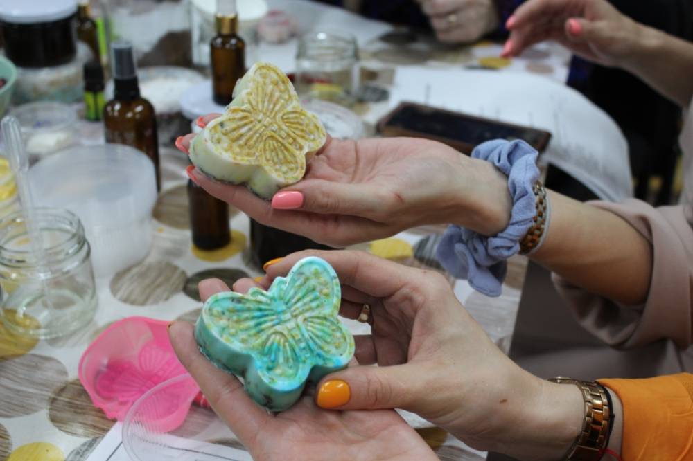 Na zdjęciu uczestniczki warsztatów prezentują na dłoniach gotowe kolorowe ziołowe mydełka.