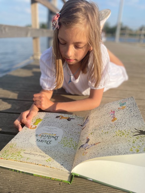 Dziewczynka czyta książkę na pomoście